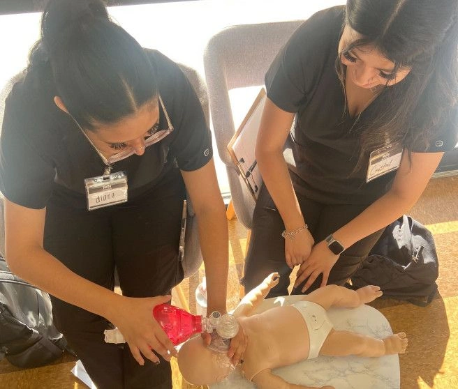 {{ school.name }} students performing CPR on test infant dummy